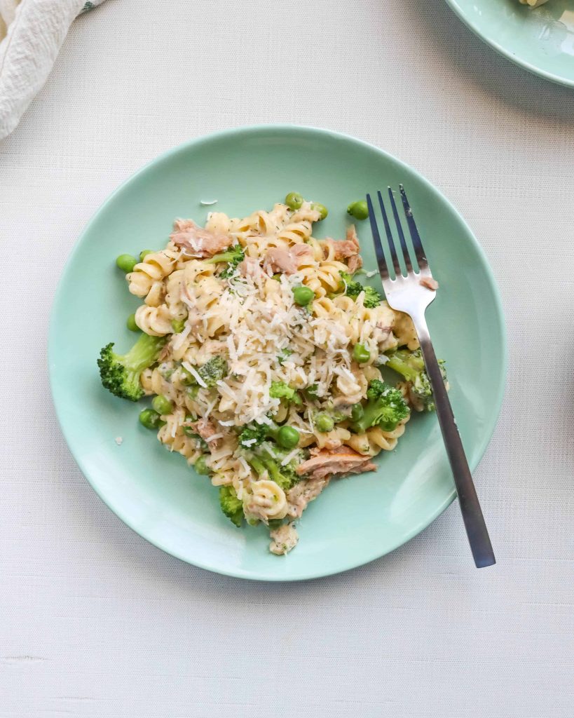 Creamy Homemade Tuna Helper on a green place topped with peas, broccoli and cheese. surrounded by bowls of peas, broccoli and cheese