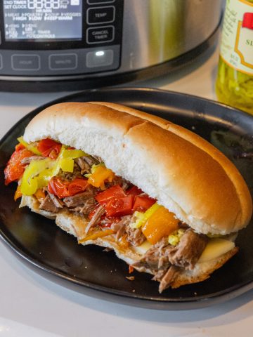 Italian beefs on a plate with slow cooker in the background
