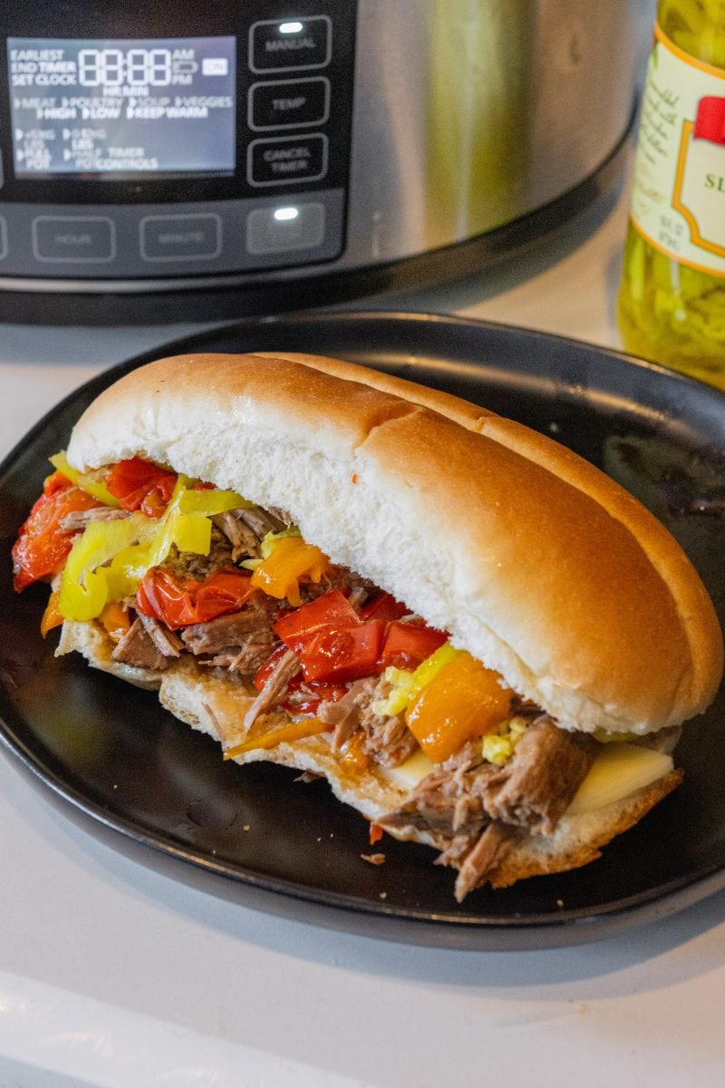 Italian beefs on a plate with slow cooker in the background 
