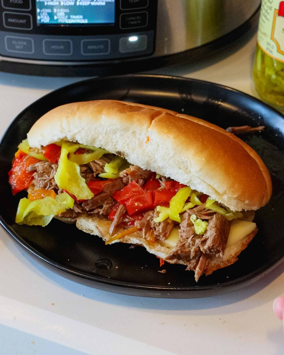 Italian beefs on a plate with slow cooker in the background