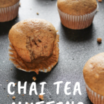 Chai tea muffins, one with a bit taken out of it, on a black surface