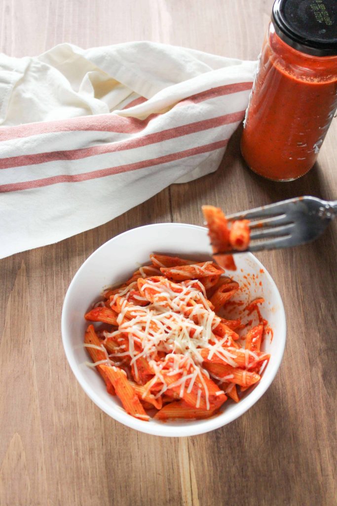 Red Pepper Penne win a bowl with a jar of sauce and a napkin next to it.  