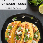 Slow Cooker Chicken Tacos topped with cilantro and cheese , on a black plate.