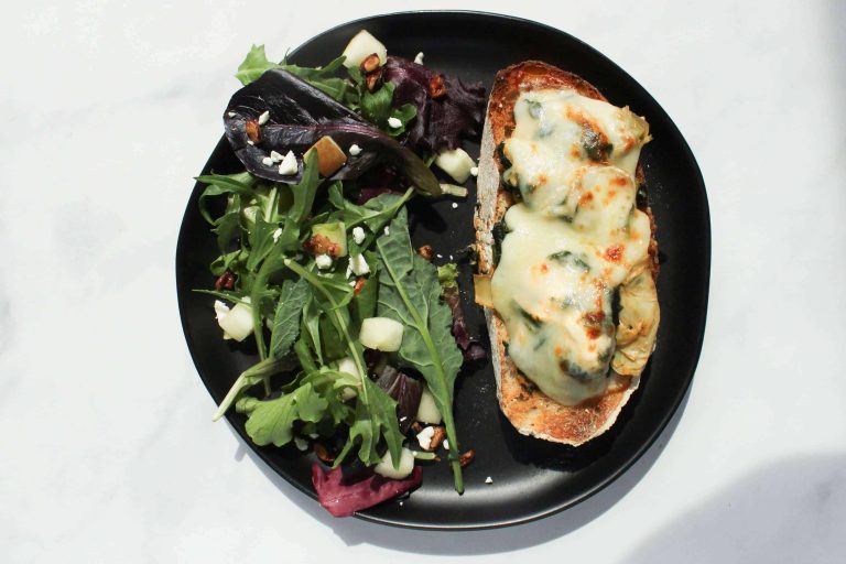 Spicy Spinach Artichoke Melt on a plate next to a salad.