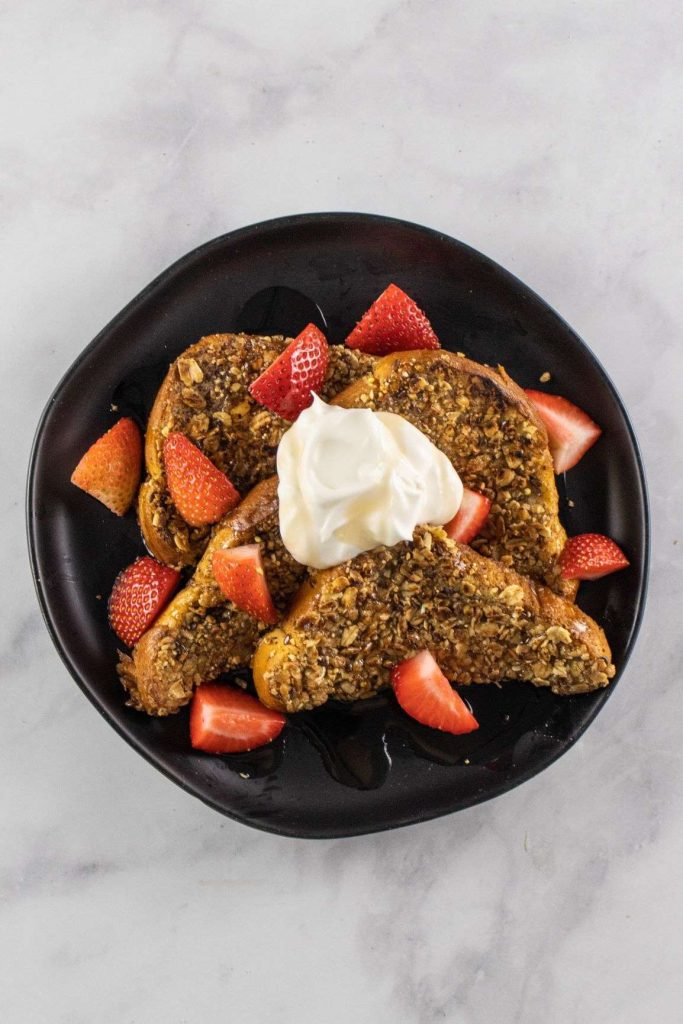 Granola French Toast on topped with strawberies and whipped cream- black pate