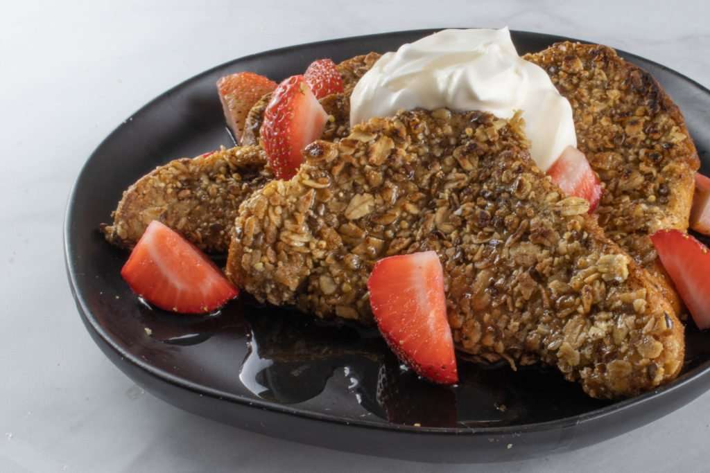 Granola French Toast on topped with strawberies and whipped cream-  black pate