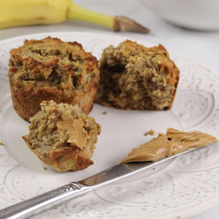 Healthy Peanut Butter Banana Muffins on a plate with a knife, next to a banana and strawberries