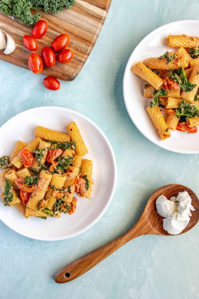 Tomato Goat Cheese Pasta on a white plate white a blue background