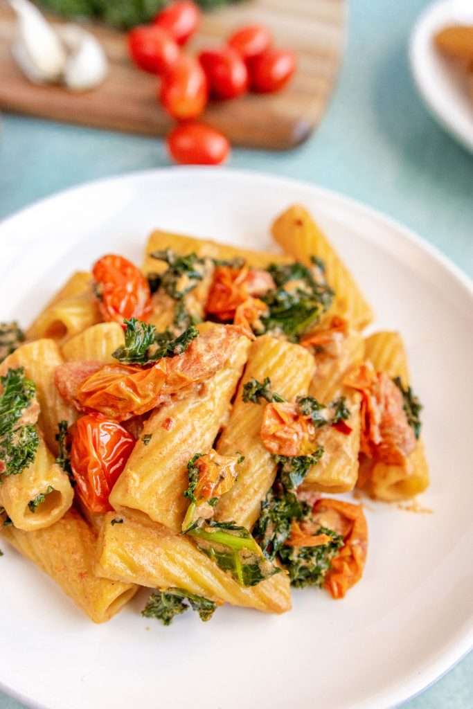 Tomato Goat Cheese Pasta on a white plate white a blue background