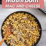Creamy Skillet Mushroom Mac and Cheese in a skillet. Next to it is a cheese grader with cheese and a napkin.