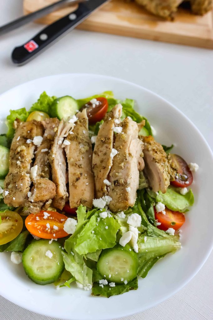 Greek Marinated Chicken Thighs  in a bowl with salad