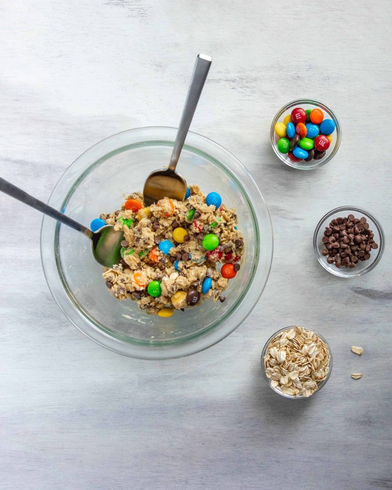 Edible Monster Cookie Dough for Two in a bowl with two spoons , surrounded by toppings