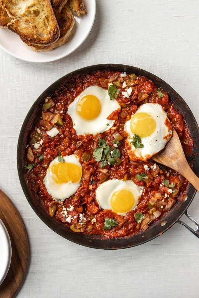 Shakshuka in a pan with a wooden spoon