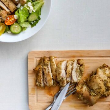 Greek Marinated Chicken Thighs in a bowl with salad