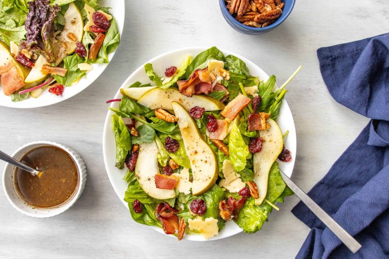 Salad with pears, made with bacon, pears, walnuts, dried cherries, and gouda cheese.