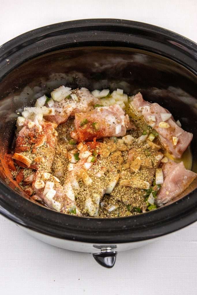 Pork carnitas ingredients in a slow cooker. 