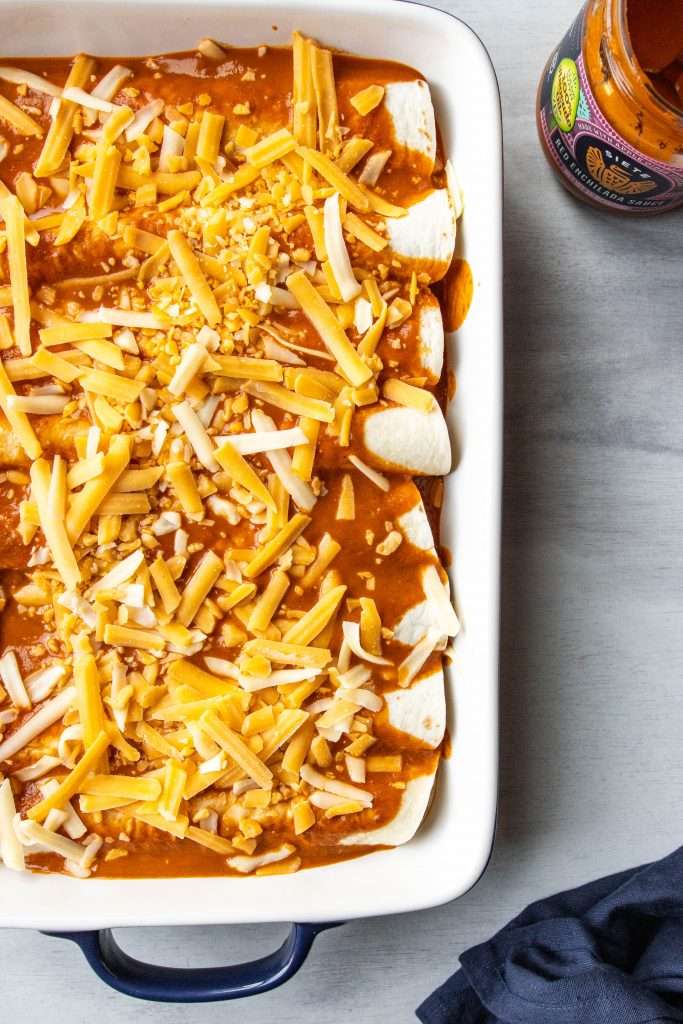 Shredded Pork Enchiladas in a baking dish with cheese on top.