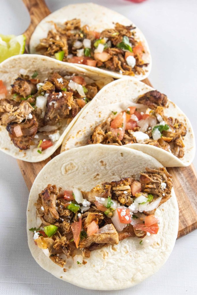 Crock Pot Pork Carnitas in a taco topped with pico de gallo. 