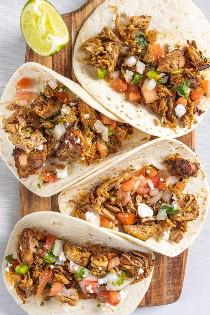 Crock Pot Pork Carnitas in a taco topped with pico de gallo. 