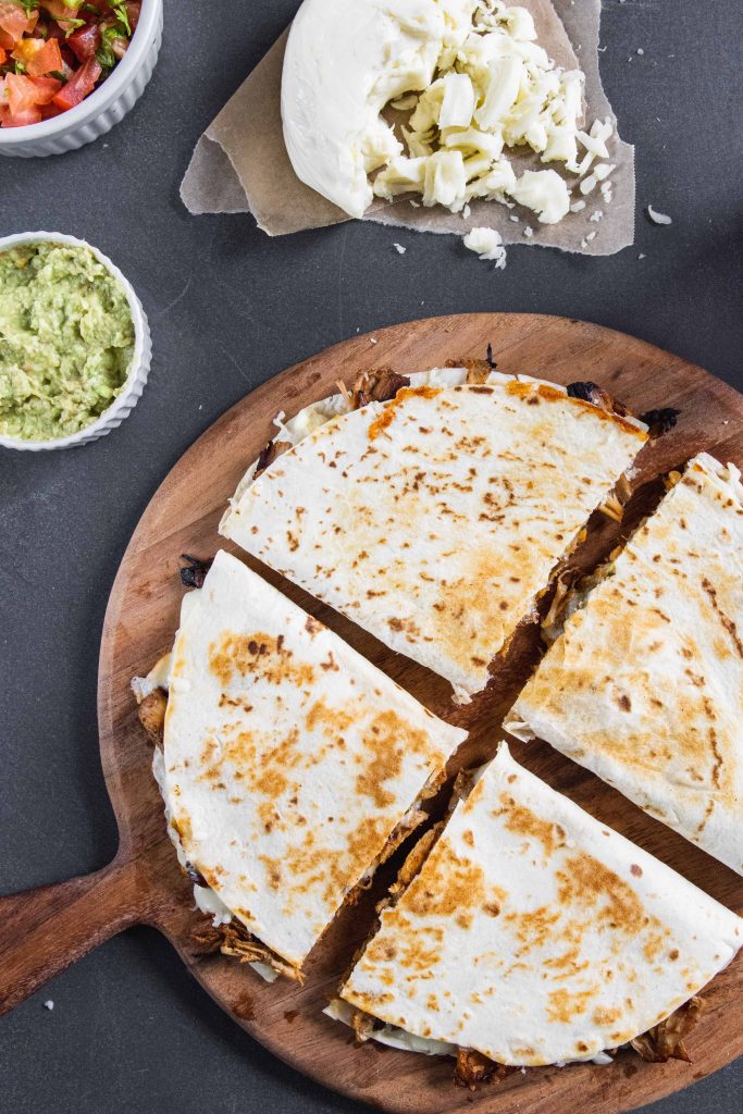  carnitas quesadilla on a wooden serving platter. 