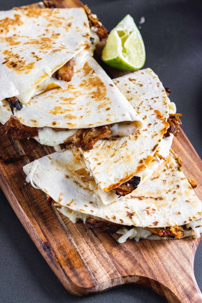 carnitas quesadilla on a wooden serving platter.