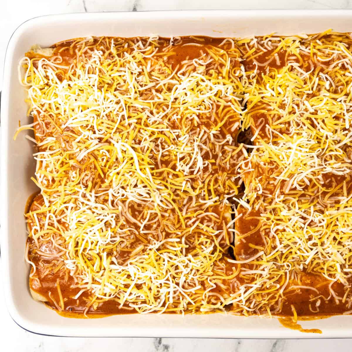 enchiladas topped with sauce and cheese - Pork Carnitas Enchiladas Recipe