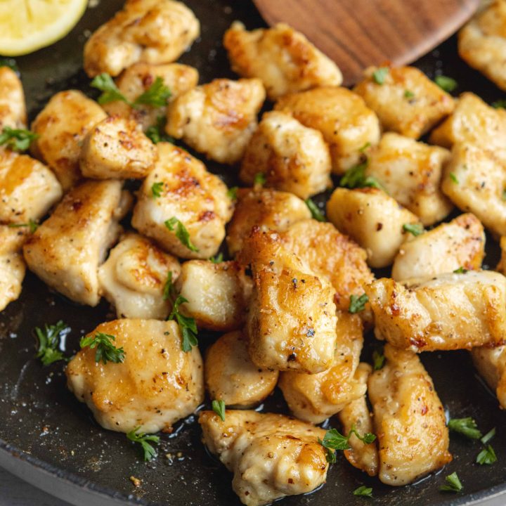 Lemon Pepper Chicken Bites in a skillet with lemons