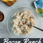 Bacon Ranch Chicken Salad on a glass bowl surrounded by crackers, ranch mix, and bacon
