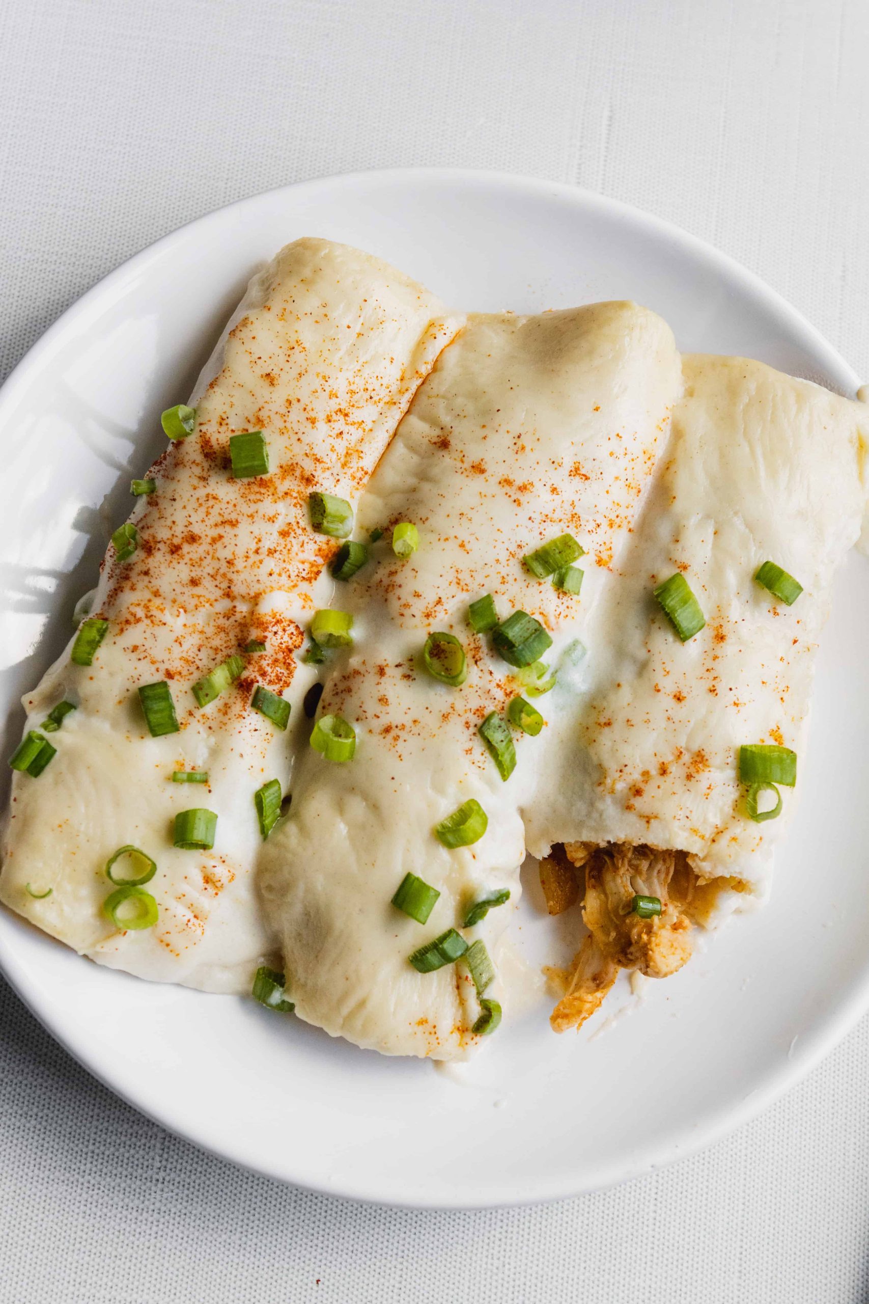 Chicken Enchiladas with sour cream sauce and green onions on top