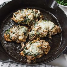 Chicken with mushrooms and spinach in a cast iron skillet.