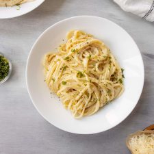 Fettuccine Alfredo in a bowl topped with parsley and pepper.