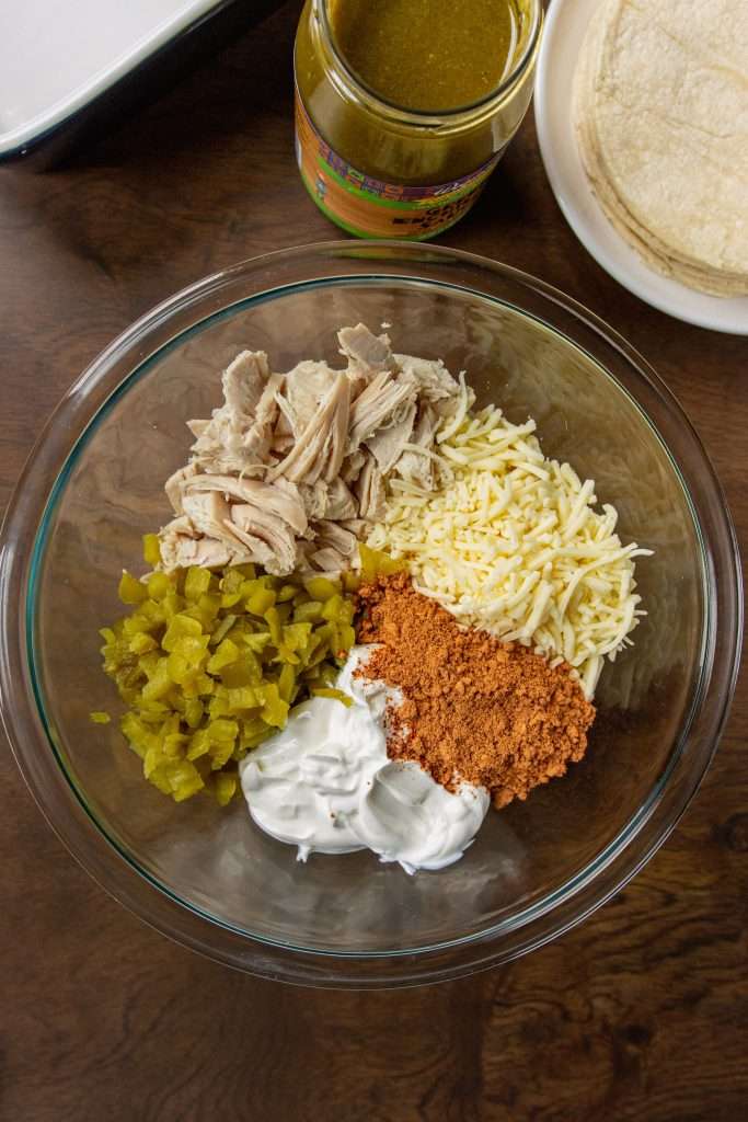 Easy Chicken Enchiladas ingredients in a bowl: chicken, cheese, taco seasoning, sour cream, green peppers
