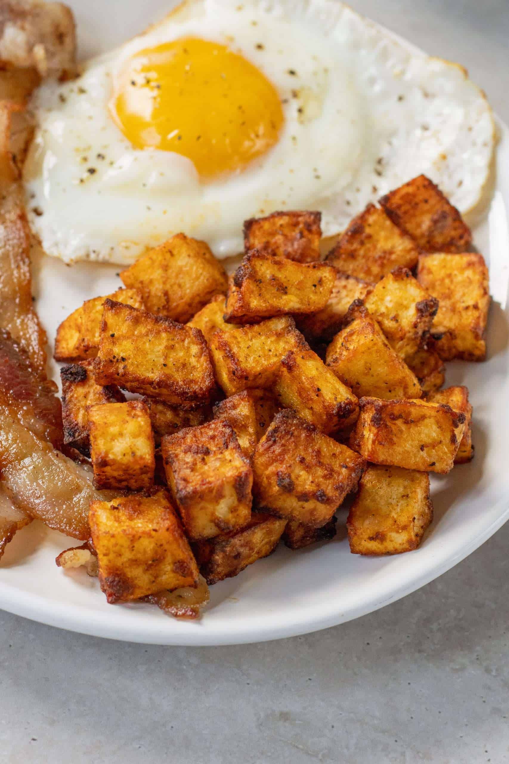 Air Fryer Home Fries with eggs and bacon on a plate