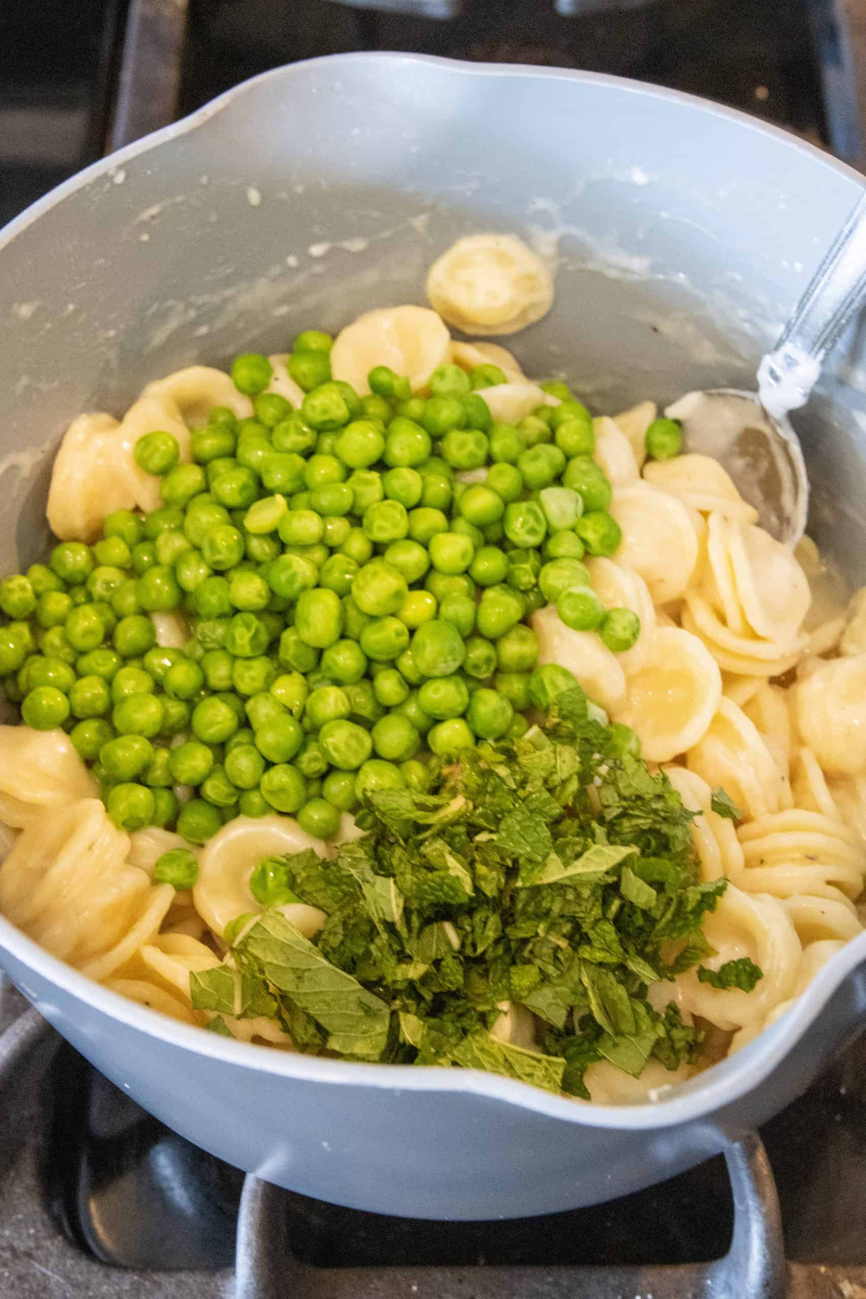 Adding peas and mint to pasta