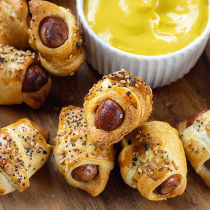 Pigs in a Blanket on a wooden plate with mustard