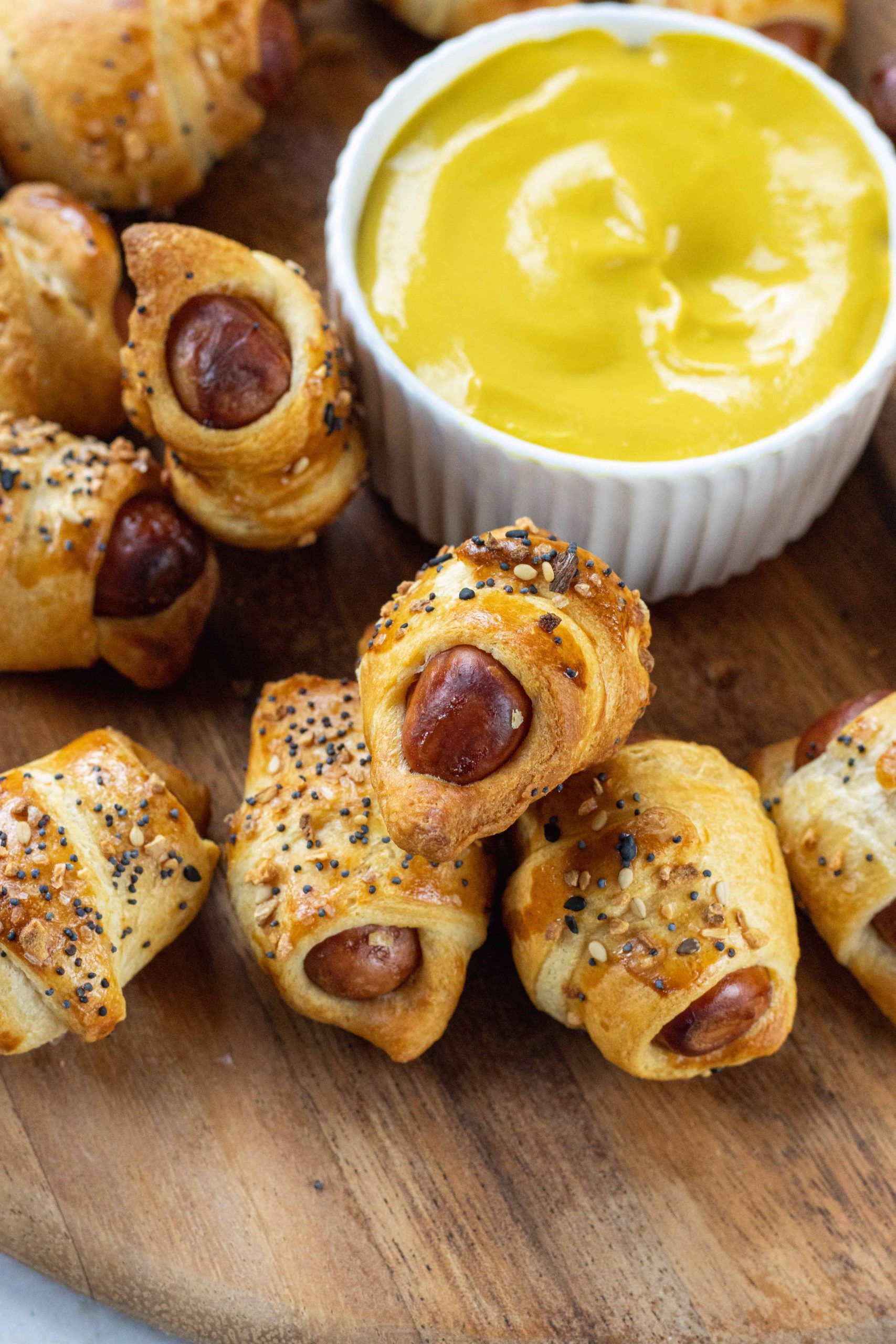 Pigs in a Blanket on a wooden plate with mustard 