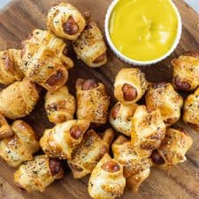 Pigs in a Blanket on a wooden plate with mustard