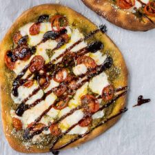 Caprese Naan Pizza on parchment paper with balsamic glaze
