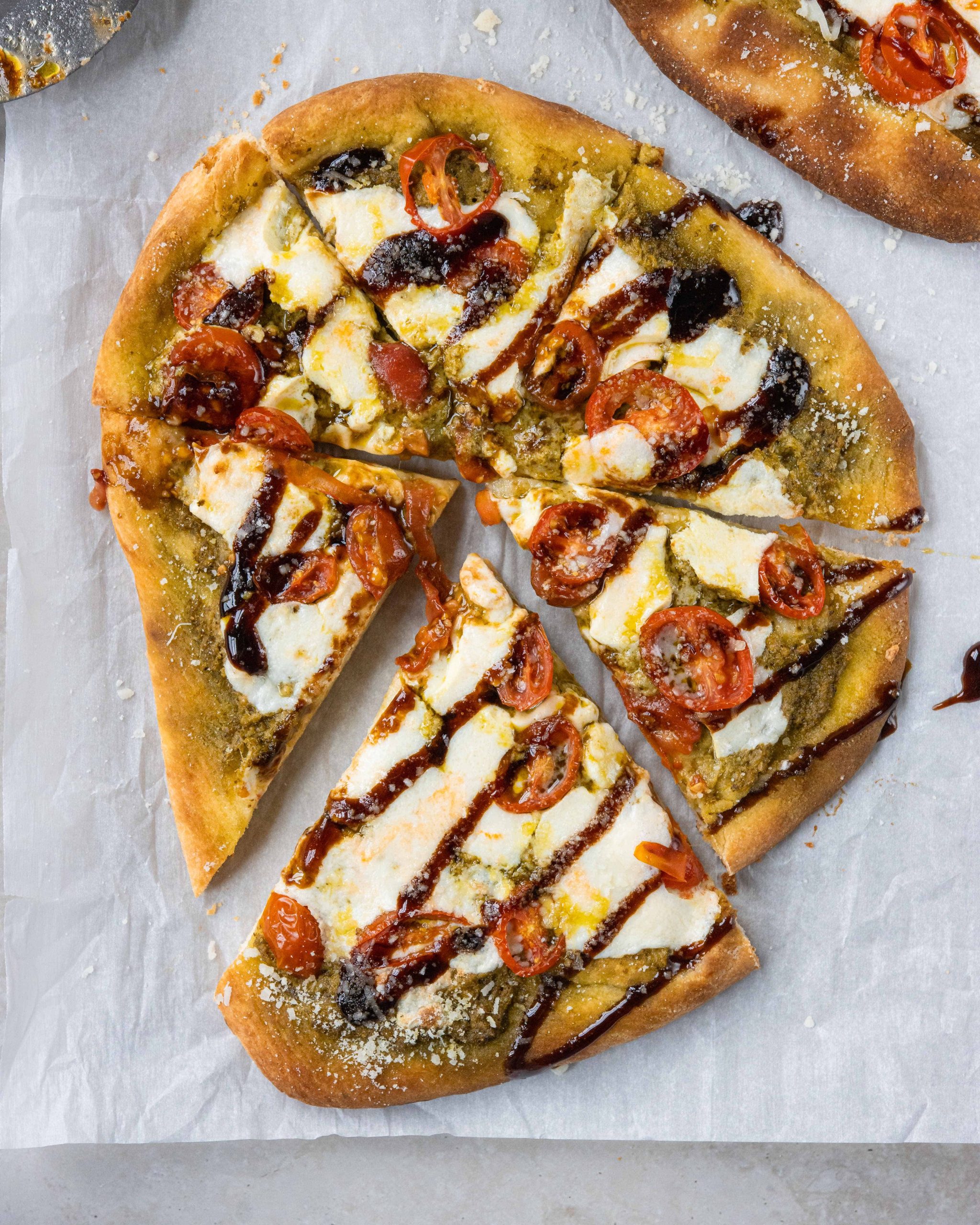 Caprese Naan Pizza  on parchment paper with balsamic glaze 