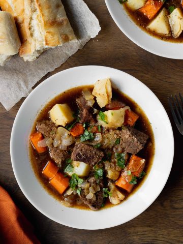Beef Stew in a bowl on a table with bread