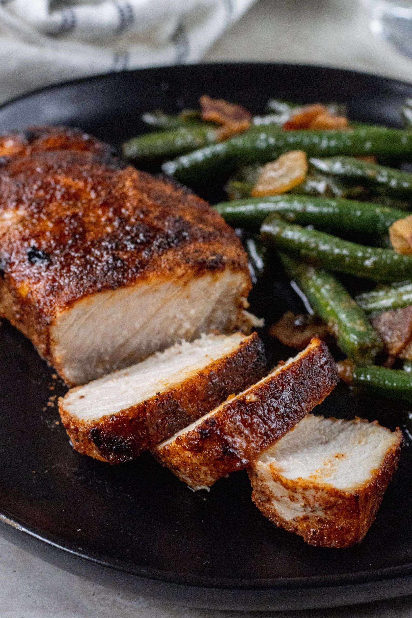 Broiled Pork Chops Cut up on a plate with green beans 