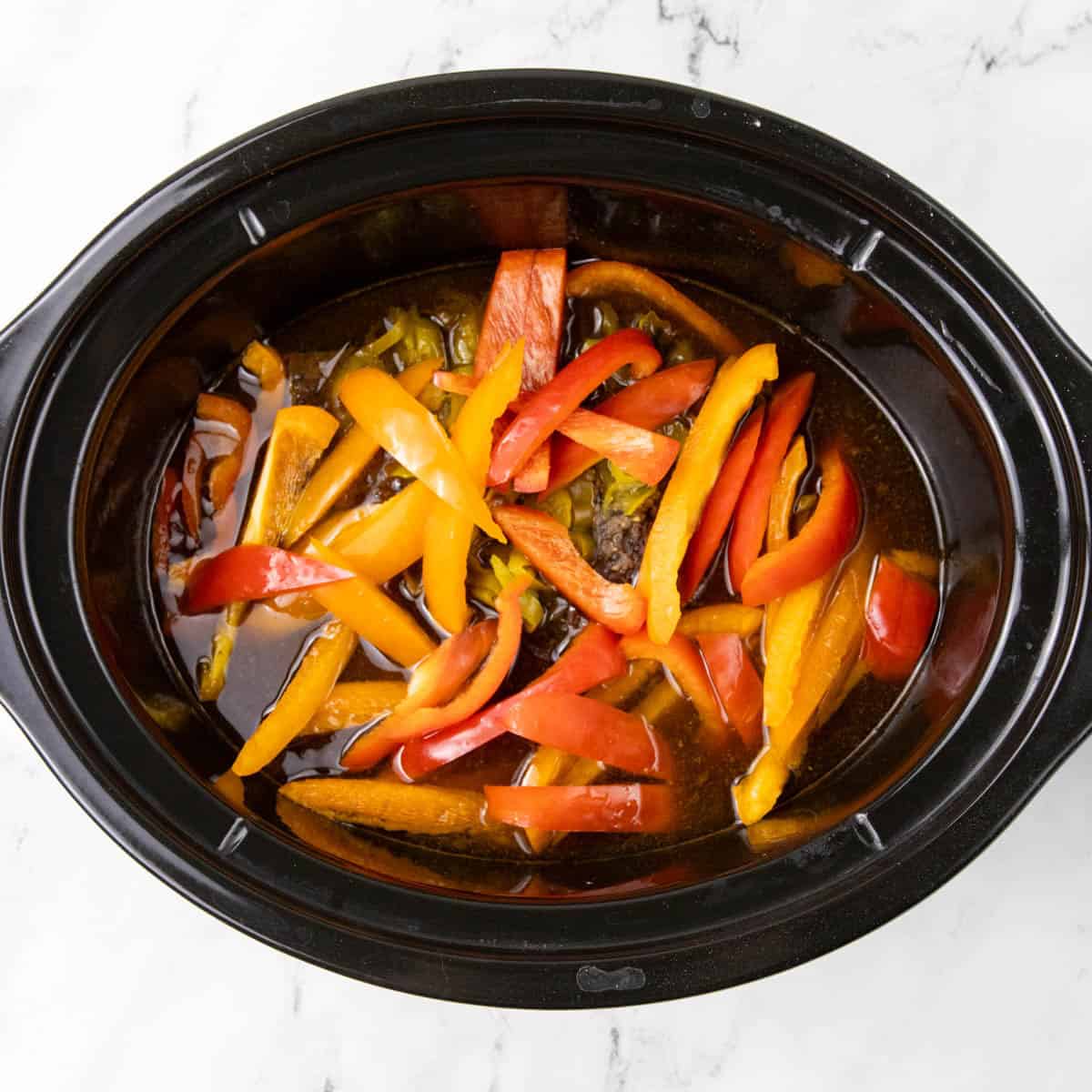 Bell peppers in slow cooker with cooked meat.