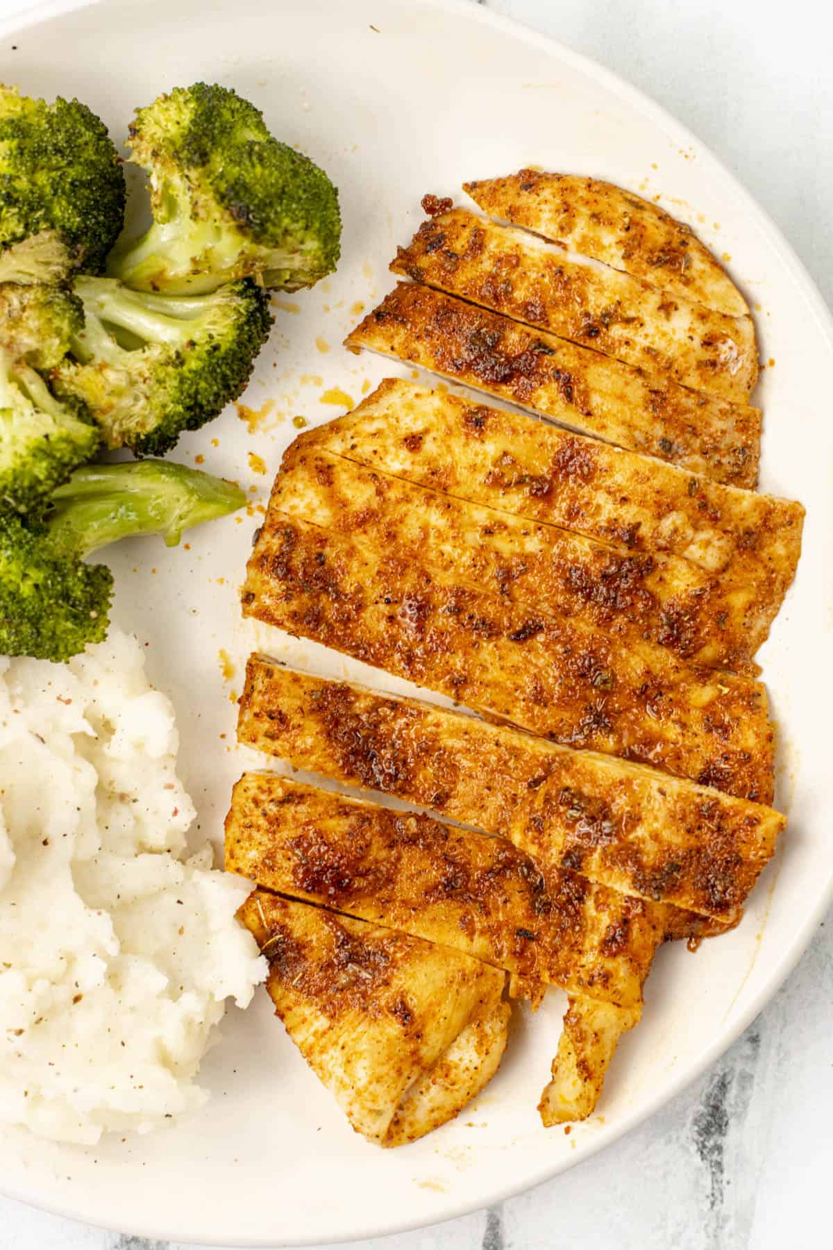 air fryer thin chicken breast on a plate with broccoli and mashed potatoes