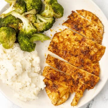 air fryer thin chicken breast on a plate with broccoli and mashed potatoes