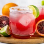 Blood Orange Margarita in a cup with ingredients in background.