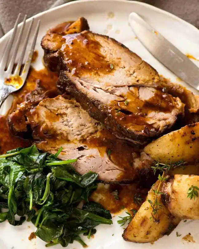 Slow Cooker Pork Loin Roast on a plate next to spinach