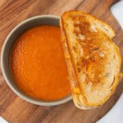 tomato soup in a bowl next to a grilled cheese sandwich