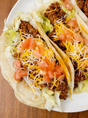 turkey tacos on a plate topped with lettuce, tomatoes, and cheese