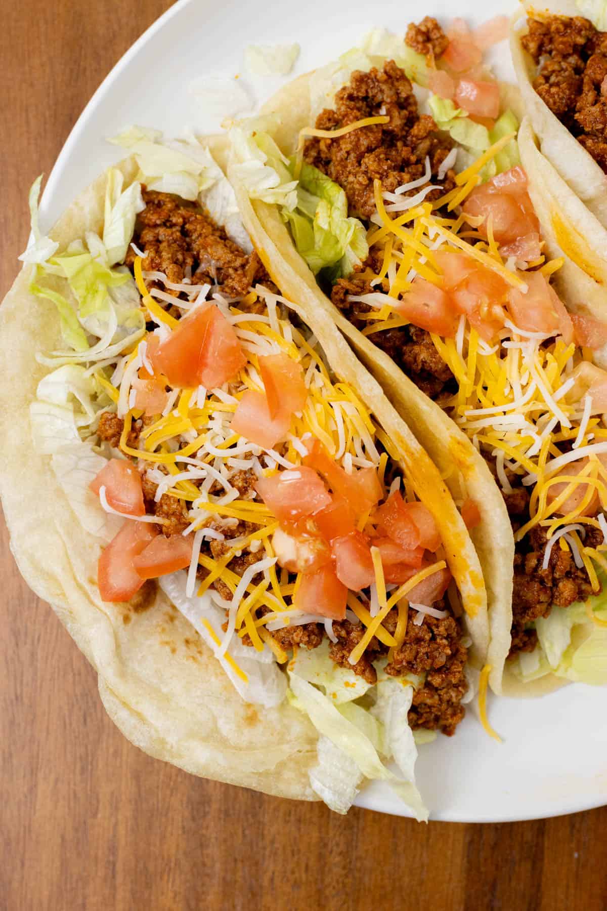 turkey tacos on a plate topped with lettuce, tomatoes, and cheese