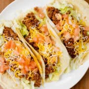 turkey tacos on a plate topped with lettuce, tomatoes, and cheese